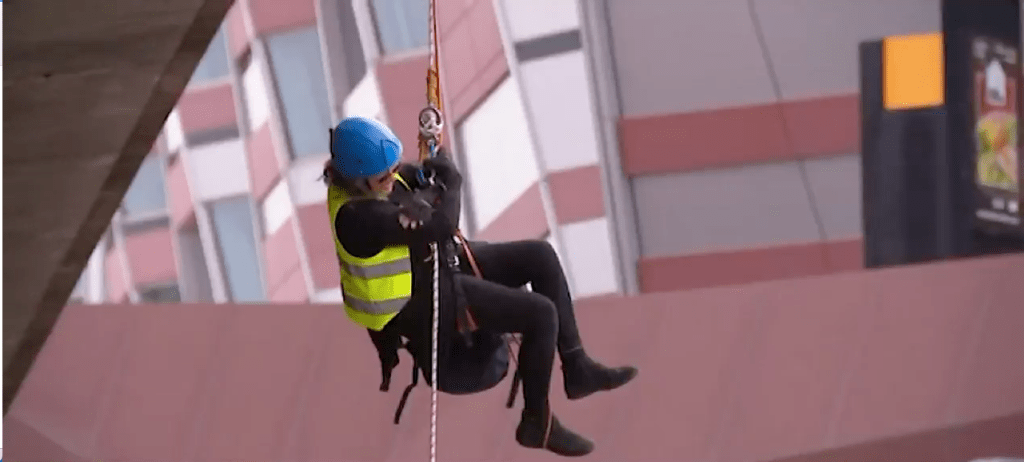 A climate protester dangles from the Morphett St bridge on North Terrace as an oil and gas conference runs at the Convention Centre. Photo: Ten News First