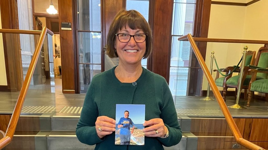 Andrea Fuller holding a picture of her father Dion Manthorpe who died peacefully under new voluntary assisted dying laws. Photo: supplied