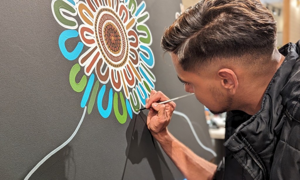 Artist Presten Warren, winner of the BHP Carrapateena PPE art competition, undertaking a live painting at BHP Olympic Dam, Roxby Downs, on Sunday. 