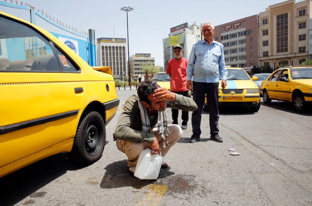 A taxi driver tries to cool down in Tehran. Photo: EPA/ABEDIN ATEHRKENAREH