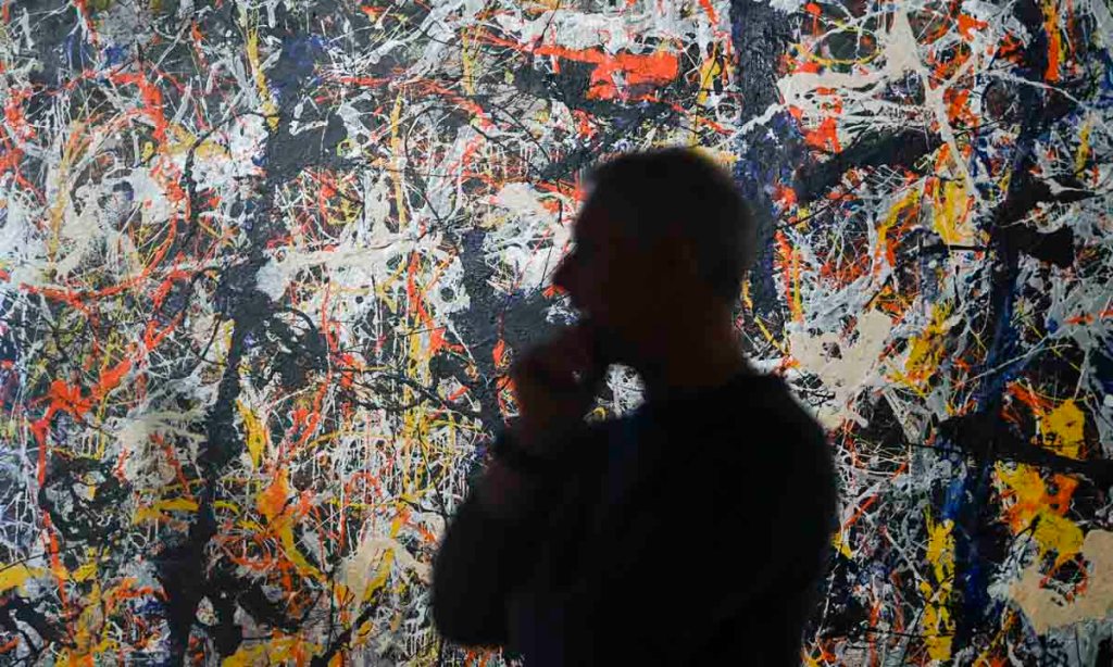 National Gallery of Australia senior paintings conservator David Wise with  'Blue Poles' by Jackson Pollock during conservation work in 2020. Photo: AAP/Lukas Coch