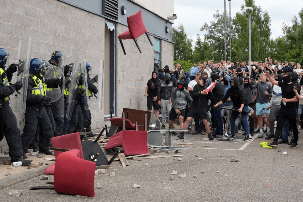 A mob confronts police trying to defend a hotel housing asylum seekers in Rotherham, England, on Sunday. Photo: AP 
